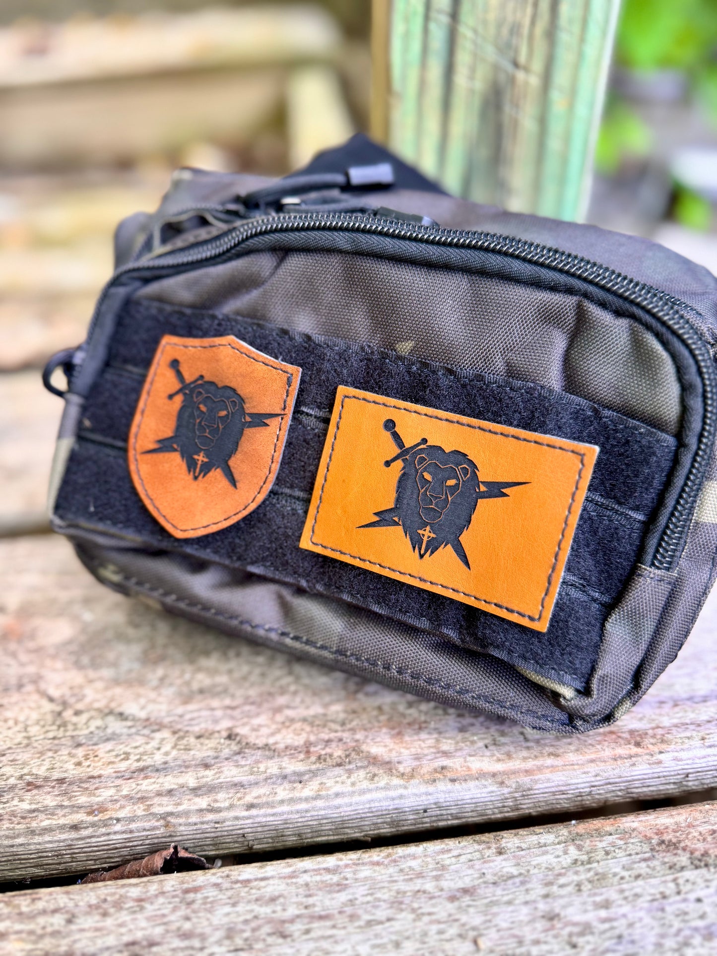 Black pouch with tan leather patches featuring bear designs on a wooden surface.